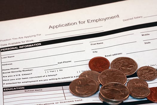 Job application for employment document on black background. Financial document with coins on the paper. Employment application for job related opportunities.