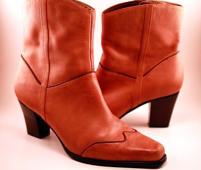 Pair of western style cowboy boots on soft background. Isolated image with dark high heels and brown trim. Western fashion, shoes and footwear for women.