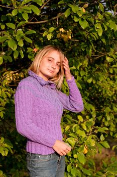 A girl in a lilac pullover and jeans in a forest
