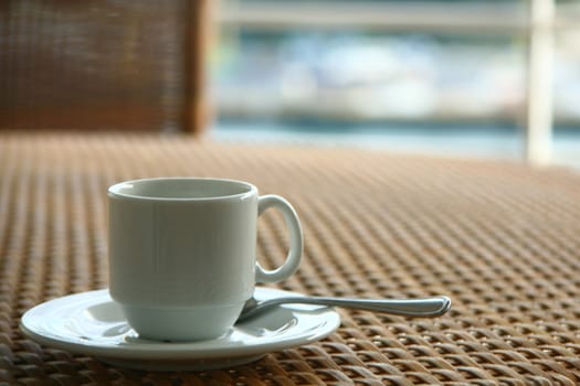 Empty white coffee cup on wicker table.