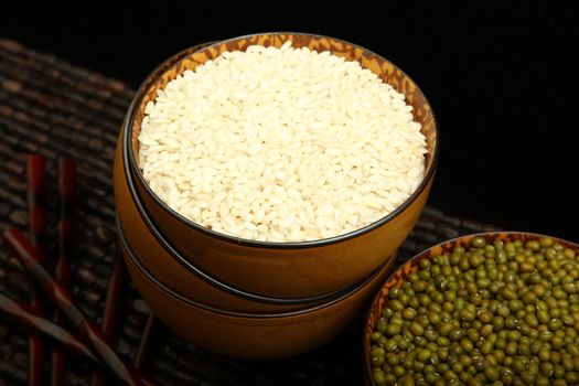 Raw arborio rice in a brown bowl in kitchen setting.