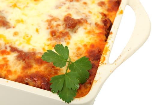 Lasagna uncut in baking dish over white background.