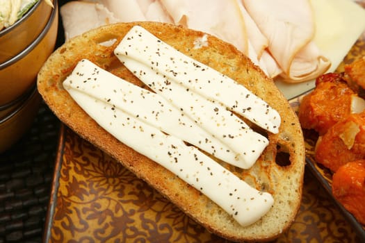 Close up of mayonaise on toasted sour dough sprinkled with black pepper.