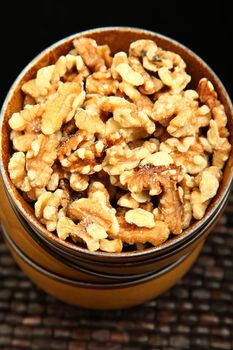 Stack of bowls filled with walnuts over black and brown background.