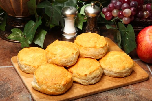 Stack of hot fresh breakfast biscuits on cutting board in kitchen.