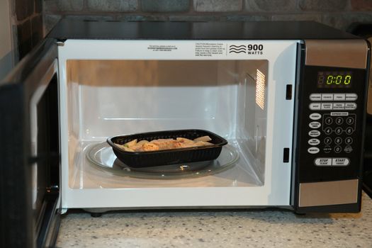Frozen chicken noodle dinner in microwave in kitchen.