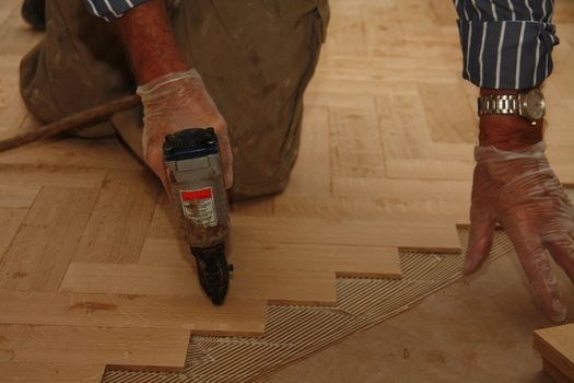 Detail of a man busy laying a wooden floor in fishbone pattern