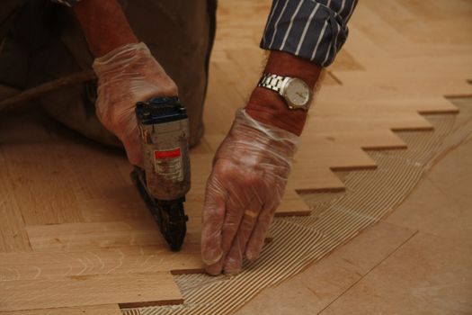 Detail of a man busy laying a wooden floor in fishbone pattern