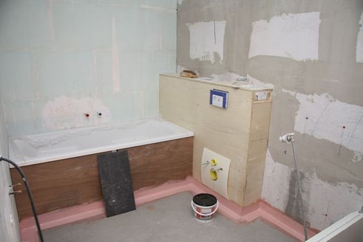 A bathroom under construction: bath and toilet are ready to be finished