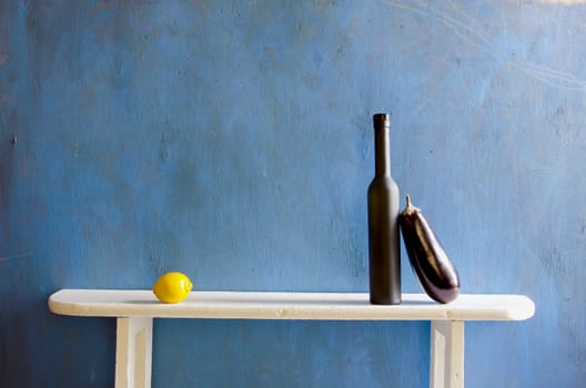 still-life with bottle and vegetables on blue background