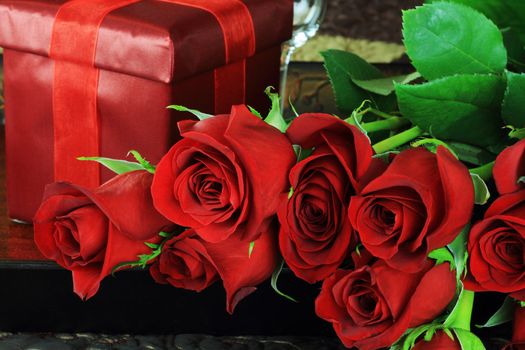 Upclose image of beautiful long stem red roses with gift in a breakfast tray on a bed.