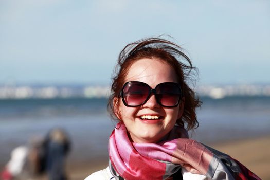 The happy girl in solar glasses on a beach