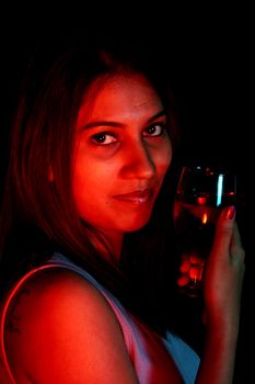 A portrait of a beautiful Indian lady drinking wine.