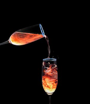 Glass of orange neon liquid pouring into another