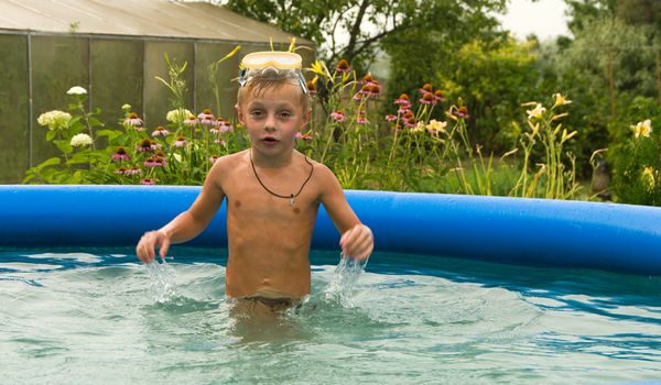 The boy bathes in dark blue inflatable pool