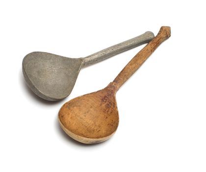 Wooden and antique pewter spoons on a white background.