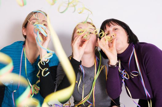 Two young women and one senior woman celebrating New year's eve. Shot taken in front of white background