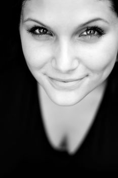 Close up of a beautiful young womans face with a friendly smile. Shallow depth of field.