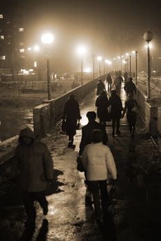 City commuters cross over the bridge in the foggy night