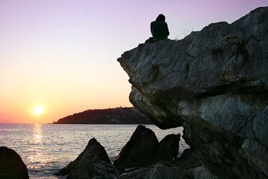 A young person sitting on a stone at sunset in Crimea, Ukraine