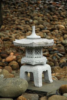 small buddhist sculpture made of stone, small stones in background