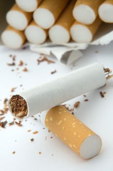 broken cigarette on white background, cigarettes in background, distance blur