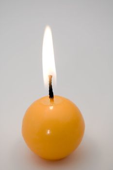 small yellow burning candle, grey background