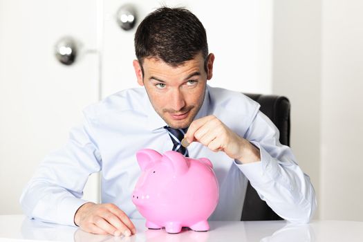 young man with pink piggy bank and coin