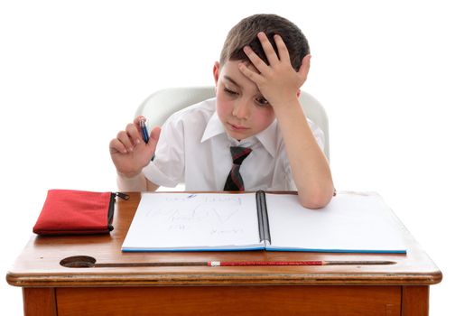 A young schoolboy sitting at a school desk in deep thought or having a problem or difficulty.   White background