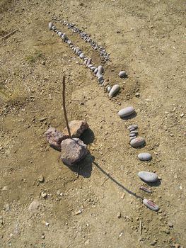 on the sand in summer with the aid of the stick and the stones made sundials in order to determine time without the wrist watch.