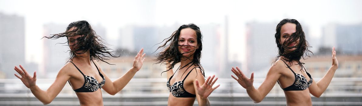 The beautiful woman dances on a roof under a rain