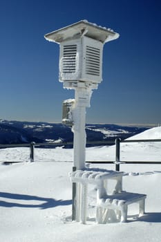 A frozen stevenson screen on the top of a Swiss mountain in winter.