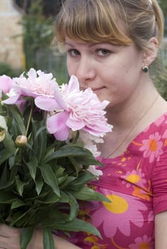 Beautiful young woman holding pink peony