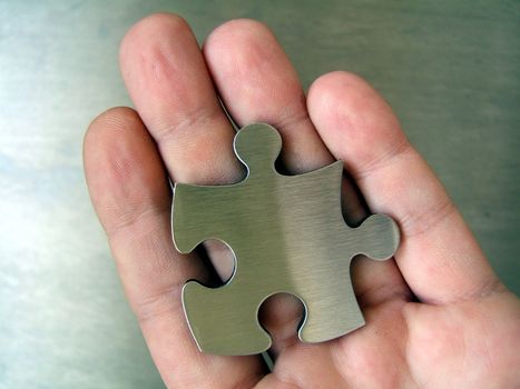 Chrome jigsaw puzzle piece on man hand