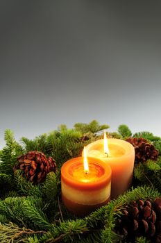 Christmas arrangement of burning candles and green spruce branches, background