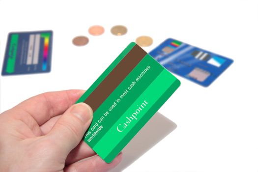 a man holding a credit card (made up fake card ) with more fake cards and coins in the background