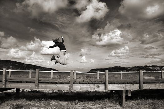 Young woman jumping for fun in a beautiful day (Black and white version)