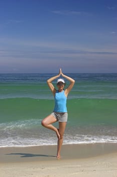 Beautiful woman making yoga exercises on the beach
