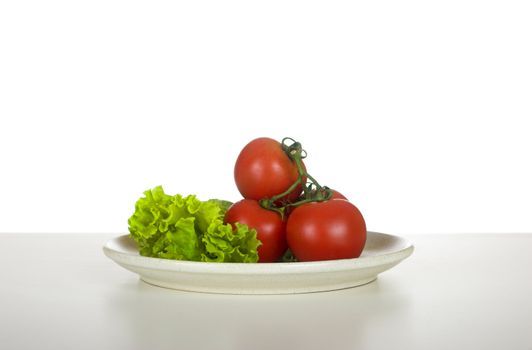 Red tomatos and lettuce in a plate over a table ready to be eaten