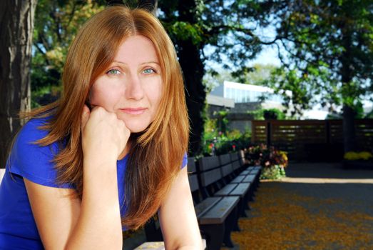 Mature woman looking sad and tired sitting on a park bench
