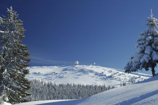 A view of the Swiss mountain of La Dole in winter. Atthe top of the mountain is an air traffic control radar dome. Space for copy in the sky.