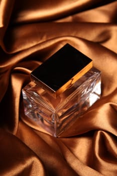 Unique parfume bottle over luxury silk background.