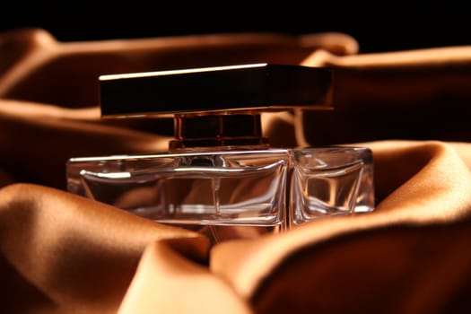 Unique parfume bottle over luxury silk background.