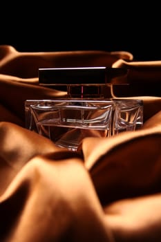 Unique parfume bottle over luxury silk background.