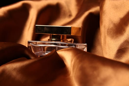 Unique parfume bottle over luxury silk background.