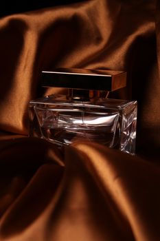 Unique parfume bottle over luxury silk background.