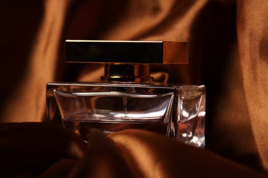 Unique parfume bottle over luxury silk background.