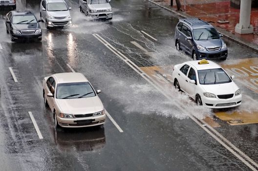 Car driving through a flooded street with huge splash