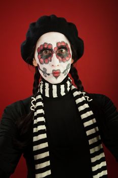 A skinny woman with ponytails made up for All Souls Day and striped scarf