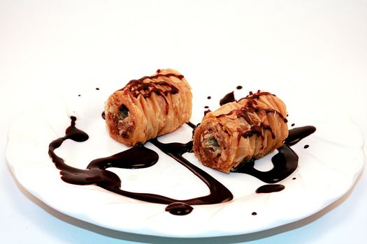 Baklava holiday Christmas dessert on white plate. Chocolate is drizzled on white plate that is isolated on white background.